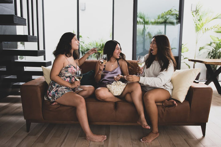 A Group of Friends Sitting on the Couch Talking while Holding Drinks